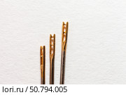 Close-up of three metal needles for visually impaired people with a special gold-plated eye on a white background. Comfortable sewing and embroidery. Top view, copy space, flat lay, macro, mock up. Стоковое фото, фотограф Виктория Катьянова / Фотобанк Лори