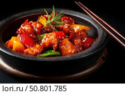 Sweet sour pork with colorful peppers, mixed vegetables served in a black bowl on dark concrete background. Traditional Chinese dish. Close-up. The meat pieces in a brown sauce glaze. Sichuan cuisine. Стоковое AI-изображение, AI-художник Марина Демидюк / Фотобанк Лори