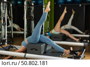 Woman in sports top and leggings doing exercises on reformer. Стоковое фото, фотограф Яков Филимонов / Фотобанк Лори