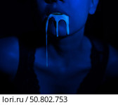A thick white liquid flows down the lips of a young European girl. Dripping down. Ultraviolet, blue light. Close-up portrait. Spit out. Стоковое фото, фотограф Михаил Решетников / Фотобанк Лори