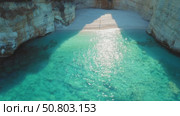 Lone woman walks on a secluded white beach bathed in sunlight and turquoise water. Hidden cove and pristine sea in summer Ionian Island of Greece. Стоковое видео, видеограф Igor Tichonow / Фотобанк Лори