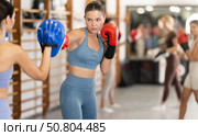 Woman works out strength and speed of boxing punch mitts with help of partner in boxing paws. Стоковое фото, фотограф Яков Филимонов / Фотобанк Лори