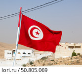 Flag of Tunisia waving against background of stone houses during daytime. Стоковое фото, фотограф Яков Филимонов / Фотобанк Лори