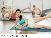 Girls perform exercises lying on side with legs straightened and narrow elastic band on shins. Стоковое фото, фотограф Яков Филимонов / Фотобанк Лори