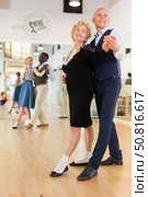 Elderly woman learning ballroom dancing movements in pair. Стоковое фото, фотограф Татьяна Яцевич / Фотобанк Лори