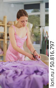 Attentive young female dressmaker cutting textile using scissors in sewing workshop. Стоковое видео, видеограф Яков Филимонов / Фотобанк Лори