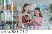Woman and her daughter stand in a pharmacy in the summer and scan the barcode of cough syrup on a mobile camera. Daughter helps her mother to use online app for pay. Стоковое видео, видеограф Яков Филимонов / Фотобанк Лори