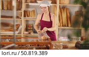Young girl seller in apron putting fresh croissant in plastic bag in bakery shop. Стоковое видео, видеограф Яков Филимонов / Фотобанк Лори