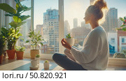 Mindful Morning: A peaceful woman holding a sprout in a sunlit room, practicing meditation and enjoying a quiet start to the day. Стоковое AI-изображение, AI-художник Данила Большаков / Фотобанк Лори