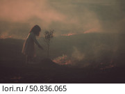 Child planting a tree in a burned landscape during sunset highlighting the importance of reforestation. Стоковое AI-изображение, AI-художник Сергей Толмачёв / Фотобанк Лори