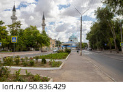 Yevpatoria, Russian Federation - July 05, 2025: Scenic street view featuring lush greenery, traditional architecture, and minarets under a cloudy sky, capturing the essence of urban tranquility. Редакционное фото, фотограф Ирина Ручушкина / Фотобанк Лори