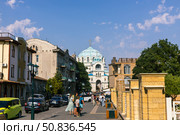 Yevpatoria, Russian Federation - July 05, 2025: Beautiful street view in a historic city with people walking, showcasing the stunning architecture and blue-domed church in the background, perfect for travel enthusiasts. Редакционное фото, фотограф Ирина Ручушкина / Фотобанк Лори