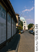 Yevpatoria, Russian Federation - July 05, 2025: Historic street view featuring charming architecture and a prominent blue-domed church in the background, showcasing cultural heritage and urban life. Редакционное фото, фотограф Ирина Ручушкина / Фотобанк Лори