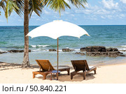 Tropical beach scene with two lounge chairs under white umbrella, overlooking a serene ocean and blue sky. Vacation concept. Copy space. Стоковое фото, фотограф Ирина Михайличенко / Фотобанк Лори
