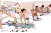 Happy girl on hands and knees doing stretch exercises for legs with resistance band on mats with group of sporty people in gym. Стоковое видео, видеограф Яков Филимонов / Фотобанк Лори