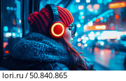 City Light Reverie: traveler absorbed in urban night view, listening music with glowing headphones, beanie, scarf, glasses, and jacket on. Стоковое AI-изображение, AI-художник Данила Большаков / Фотобанк Лори