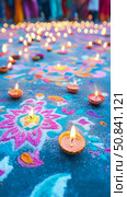 Diwali celebration: Rangoli art illuminated with diya lamps, creating a warm glow for the festive season. Стоковое AI-изображение, AI-художник Данила Большаков / Фотобанк Лори