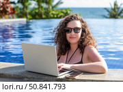 Young freelancer traveler woman working remotely on computer at pool in luxury resort during her summer holiday. Work from anywhere, Technology and lifestyle concept, copy space. High quality photo. Стоковое фото, фотограф Ирина Михайличенко / Фотобанк Лори
