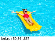 Happy little girl in red swimsuit lies comfortably on yellow inflatable mattress in swimming pool with blue water on warm summer day on tropical vacation. Happiness, freedom, childhood concept. Стоковое фото, фотограф Ирина Михайличенко / Фотобанк Лори