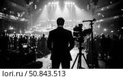 Event coverage: Silhouette of a man in suit overseeing stage production, capturing performance, show broadcast with camera crew at theater. Стоковое AI-изображение, AI-художник Данила Большаков / Фотобанк Лори