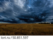 Dark storm clouds in an agricultural field in autumn. An impending storm, hurricane or thunderstorm. Стоковое фото, фотограф Емельянов Евгений Викторович / Фотобанк Лори