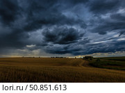 Dark storm clouds in an agricultural field in autumn. An impending storm, hurricane or thunderstorm. Стоковое фото, фотограф Емельянов Евгений Викторович / Фотобанк Лори