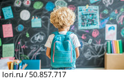 Back to school concept: Young pupil with rucksack in classroom interior, in front of blackboard with drawings. Стоковое AI-изображение, AI-художник Данила Большаков / Фотобанк Лори