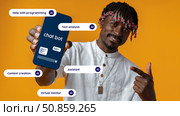 Man showcasing chatbot app features with AI capabilities in a vibrant orange background. Стоковое фото, фотограф Сергей Толмачёв / Фотобанк Лори