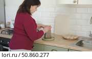 Senior active woman cooking lunch at home in modern kitchen. Healthy eating, food and culinary concept. Hands of old lady with knife chopping vegetables, grating carrots. Elderly female cook a soup. Стоковое видео, видеограф Марина Демидюк / Фотобанк Лори