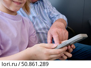 Granddaughter showing smartphone to grandfather. Portrait of a cute girl playing or typing on her smartphone while sitting in a cafe with her grandfather. Стоковое фото, фотограф Терехова Марина / Фотобанк Лори