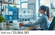 Modern office interior with a young female analyst working at two monitors. The screens display dashboards, graphs, charts and analytical data. The workplace is organized professionally, in a bright environment with minimalist elements and green plants. The image is perfect for illustrating business, analytics, remote work, IT, finance, marketing and corporate environment topics. Стоковое AI-изображение, AI-художник Анна Кривицкая / Фотобанк Лори