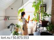 Portrait Woman in rubber gloves and apron manually cleaning in bathroom with rag cleaner and mop inside interior with home plants. Restoring order and cleanliness, cleaning servise. Стоковое фото, фотограф Ольга Симонова / Фотобанк Лори