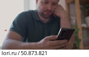 Man using his cellphone. Handsome guy use mobile phone at home. Male browses social networks, gaming, does shopping online, chats with friends, writes or reads messages. Close up. 4k video footage. Стоковое видео, видеограф Марина Демидюк / Фотобанк Лори