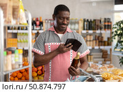 African man customer at shop scans QR code on beer bottle using phone camera. Стоковое фото, фотограф Яков Филимонов / Фотобанк Лори