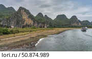 A calm and picturesque river. The water foams on the pebbly shore. Tourist ships sail in the riverbed. Mountains against the sky and clouds. China. Li River. Li Jiang. Guilin. Стоковое фото, фотограф Вера Ивановна Кубарева / Фотобанк Лори