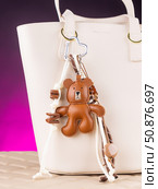 Close-up of a stylish leather bag accessory featuring a detailed leather bear charm no white bag. Стоковое фото, фотограф Виталий Сова / Фотобанк Лори