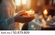Candlelight Serenity: A woman holds a glowing candle in her hands, symbolizing hope, peace, and tranquility. Стоковое AI-изображение, AI-художник Данила Большаков / Фотобанк Лори