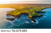 Coastal Splendor: A serene aerial showcasing sun-kissed cliffs meeting the azure ocean, backdrop of patchwork fields at sunset, perfect for travel promotion. Стоковое AI-изображение, AI-художник Данила Большаков / Фотобанк Лори
