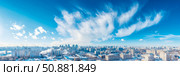 Winter Cityscape Under a Dramatic Sky: A panoramic scene of a snow-covered metropolis beneath dynamic, wispy cloud formation. Стоковое AI-изображение, AI-художник Данила Большаков / Фотобанк Лори