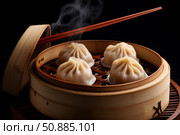 Steaming hot dumplings served in traditional bamboo steamer with chopsticks. Стоковое AI-изображение, AI-художник Иван Рябоконь / Фотобанк Лори