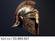 Golden corinthian helmet with red plume evoking ancient warriors on dark background. Стоковое AI-изображение, AI-художник Иван Рябоконь / Фотобанк Лори