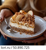 A close-up of a delicious dessert - cheesecake with caramelized apples and a crispy crumble. The layered structure of the pie with a creamy filling, juicy fruits and a golden crust looks especially delicious on a ceramic plate in your hands. Ideal for illustrating the themes of food, comfort, home recipes and cooking. Стоковое AI-изображение, AI-художник Анна Кривицкая / Фотобанк Лори