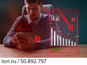 Financial analyst reviewing alarming cryptocurrency trends and market decline in modern office setting. Стоковое фото, фотограф Сергей Толмачёв / Фотобанк Лори