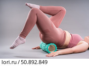 Fat woman in sportswear use myofascial release massage mfr roll on gray background, pelvic floor muscle exercise. Стоковое фото, фотограф Станислав Тарко / Фотобанк Лори