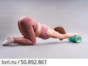 Fat woman in sportswear use myofascial release massage mfr roll on gray background, pelvic floor muscle exercise. Стоковое фото, фотограф Станислав Тарко / Фотобанк Лори