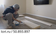 Man Professional carpenter painting wooden boards with white paint using roller brush in modern interior room during home renovation construction. Painting of wooden shelving. furniture assembly. Стоковое видео, видеограф Сергей Тимофеев / Фотобанк Лори