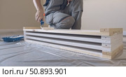 Man Professional carpenter painting wooden boards with white paint using roller brush in modern interior room during home renovation construction. Painting of wooden shelving. furniture assembly. Стоковое видео, видеограф Сергей Тимофеев / Фотобанк Лори