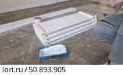 Man Professional carpenter painting wooden boards with white paint using roller brush in modern interior room during home renovation construction. Painting of wooden shelving. furniture assembly. Стоковое видео, видеограф Сергей Тимофеев / Фотобанк Лори