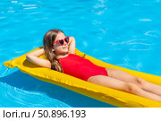 Top view little girl in red swimsuit lies comfortably on inflatable mattress in swimming pool with blue water on warm summer day on tropical vacation. Relaxation, fun, carefree childhood concept. Стоковое фото, фотограф Ирина Михайличенко / Фотобанк Лори