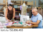 Elderly man sewing, female assistant attaching template to fabric. Стоковое фото, фотограф Яков Филимонов / Фотобанк Лори